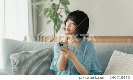 A woman thinking while using her smartphone A woman thinking while using her smartphone 140710470