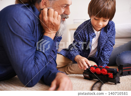 Grandfather, grandson and play with toy, train and fun in home or house with joy. Man, child and happiness with smile, youth and childhood development for future growth and bonding or care together 140710581