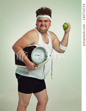 Scale, man and portrait with apple for health, fitness or nutrition isolated on gray studio background mockup. Plus size, body and eating fruit for weight loss diet of male person with tape measure 140710724