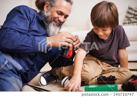 Grandfather, laugh and toy train with boy child, playing and bonding in family lounge. Grandpa, young kid and childhood development with games and fun, quality time and love with elderly retired man Grandfather, laugh and toy train with boy child, playing and bonding in family lounge. Grandpa, young kid and childhood development with games and fun, quality time and love with elderly retired man 140710747