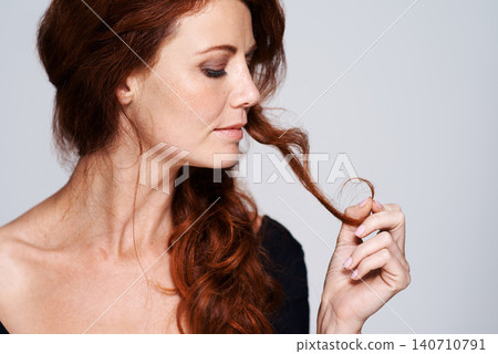 Woman, haircare and confident with treatment in studio on white background, satisfied and look down. Touch, female person and natural for healthy hair with for routine, repair and fresh for beauty. Woman, haircare and confident with treatment in studio on white background, satisfied and look down. Touch, female person and natural for healthy hair with for routine, repair and fresh for beauty. 140710791