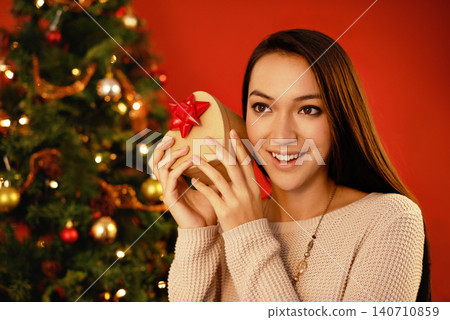 Happy, smile and Christmas with woman, gift box and parcel on a red studio background. Excited, person and girl with Xmas present and package with surprise and guessing with giveaway prize or holiday Happy, smile and Christmas with woman, gift box and parcel on a red studio background. Excited, person and girl with Xmas present and package with surprise and guessing with giveaway prize or holiday 140710859
