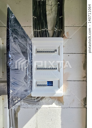 Electrical fuse box with circuit breakers mounted on a concrete wall during renovation. Electrical fuse box with circuit breakers mounted on a concrete wall during renovation. 140711064