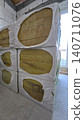 Stacked mineral wool insulation packs sit in a room with unfinished aerated concrete block walls. 140711076