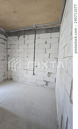 Empty room with aerated concrete walls and electrical wiring during residential construction. 140711077