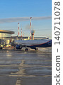 Commercial passenger airplane docked at a terminal boarding bridge under a clear morning sky. 140711078
