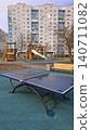 Empty blue table tennis table stands in an urban playground with residential apartment buildings behind. 140711082