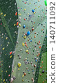 Empty indoor climbing wall features colorful holds for diverse climbers of all ages and genders. 140711092