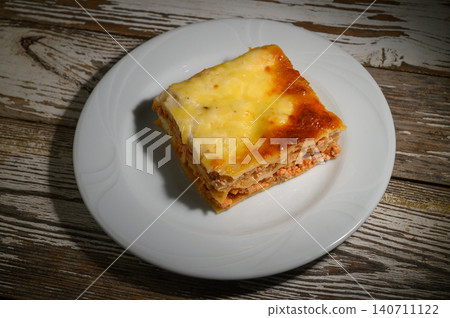 Deliciously baked layers of meat and cheese create a perfect comfort food experience at a cozy dinner setting Deliciously baked layers of meat and cheese create a perfect comfort food experience at a cozy dinner setting 140711122