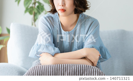 A woman sitting on a sofa and thinking 140711321