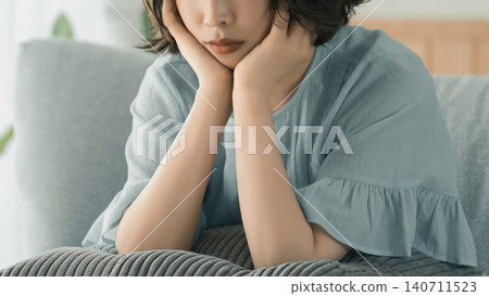 A woman sitting on a sofa and thinking A woman sitting on a sofa and thinking 140711523