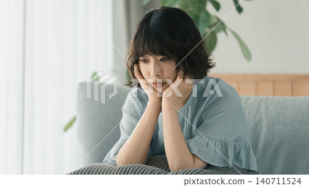 A woman sitting on a sofa and thinking A woman sitting on a sofa and thinking 140711524