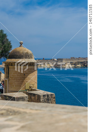 Historic limestone watchtower turret on Valletta fortification wall overlooking blue Mediterranean Sea and Fort in sunny Malta 140711585