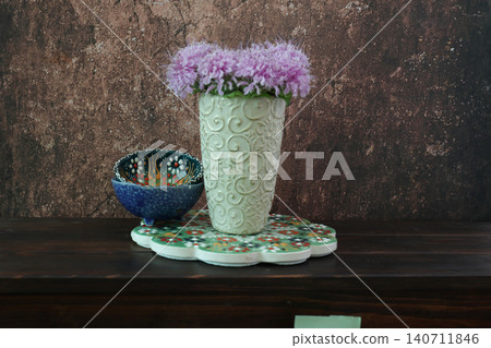 A bouquet of monarda flowers in a vase and colorful tableware A bouquet of monarda flowers in a vase and colorful tableware 140711846