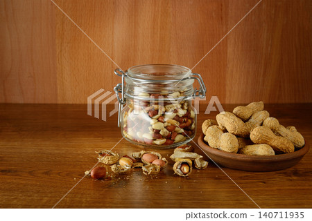 Shelled Peanuts in Glass Jar and Whole Nuts in Clay Bowl Shelled Peanuts in Glass Jar and Whole Nuts in Clay Bowl 140711935