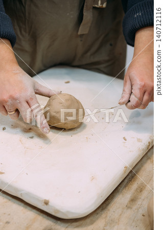 Clay shaping. Pottery workshop. Unrecognizable woman artisan creative hand cutting raw with thread using in ceramic artistic workplace. Clay shaping. Pottery workshop. Unrecognizable woman artisan creative hand cutting raw with thread using in ceramic artistic workplace. 140712116