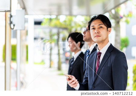 A man in a suit waiting for a bus at a bus stop. A man in a suit waiting for a bus at a bus stop. 140712212