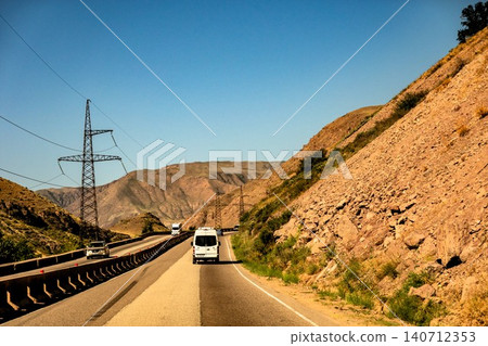 Driving Through Mountain Landscapes and Rural Highways in Chuy Region Kyrgyzstan Beneath Clear Sky Driving Through Mountain Landscapes and Rural Highways in Chuy Region Kyrgyzstan Beneath Clear Sky 140712353