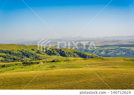 Layers of green mountains and hills in the haze during sunset. Panoramic View of Green hills and Meadow. 140712629