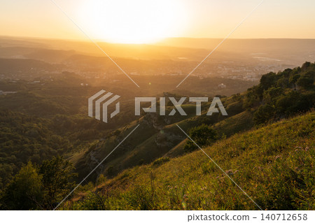View of the mountains and Kislovodsk from the observation decks of the Kislovodsk Park. Evening sunset over the mountains of Kislovodsk. View of the mountains and Kislovodsk from the observation decks of the Kislovodsk Park. Evening sunset over the mountains of Kislovodsk. 140712658