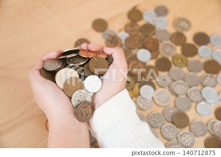 A hand holding a large amount of coins 140712875