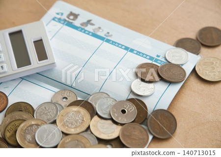 A pocket money ledger, a calculator, and lots of coins. 140713015