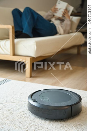 一個人在沙發上打盹,旁邊放著一台掃地機器人。 一個人在沙發上打盹,旁邊放著一台掃地機器人。 140713105
