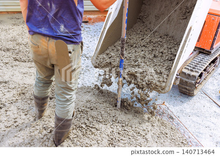 Worker uses mixer to pour wet concrete onto gravel while preparing construction project Worker uses mixer to pour wet concrete onto gravel while preparing construction project 140713464