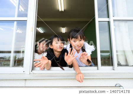 一名小學生打開教室窗戶,微笑地向外揮手。 一名小學生打開教室窗戶,微笑地向外揮手。 140714178