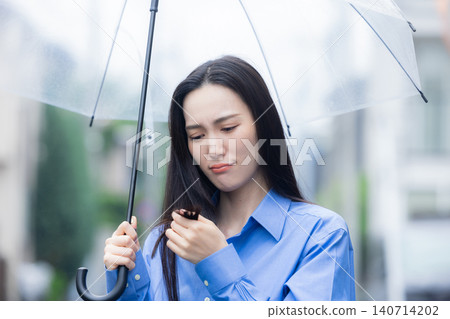 A young woman holding an umbrella in the rain 140714202