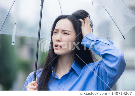 A young woman holding an umbrella in the rain 140714207
