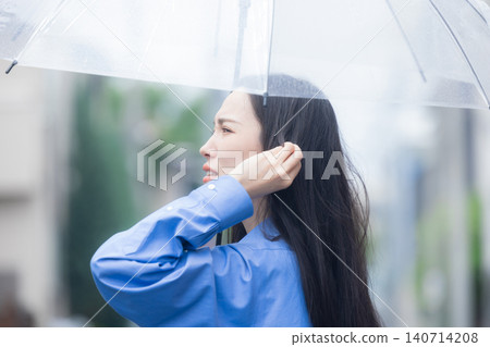 A young woman holding an umbrella in the rain 140714208