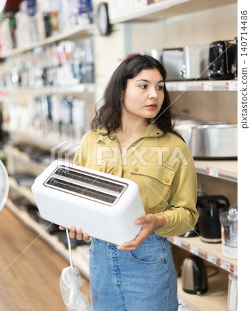 Latina woman looking at the assortment of toasters in the store 140714486