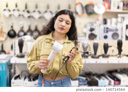 Young woman choose hair dryer at hardware store Young woman choose hair dryer at hardware store 140714564