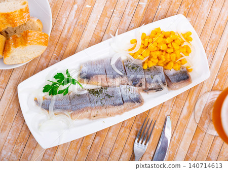 Sliced pickled herring fillet with corn and onions on plate Sliced pickled herring fillet with corn and onions on plate 140714613
