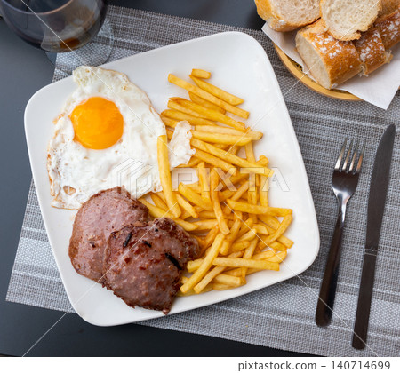 Plate with prepared food pork chop with french fries and fried egg closeup Plate with prepared food pork chop with french fries and fried egg closeup 140714699