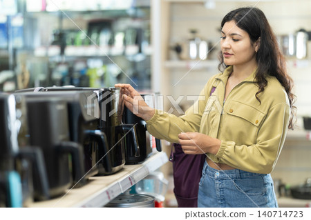 Young woman choosing air fryer at household appliances store Young woman choosing air fryer at household appliances store 140714723