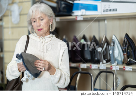 Elderly woman buys an iron with different modes 140714734