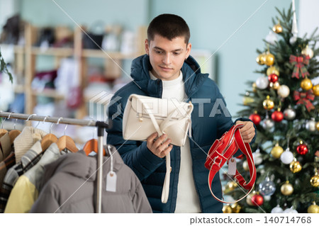 Guy choosing a handbag for a gift in the store Guy choosing a handbag for a gift in the store 140714768