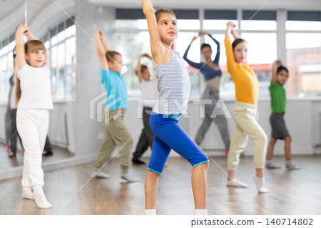 Children studying modern style dances with female teacher in dance class Children studying modern style dances with female teacher in dance class 140714802