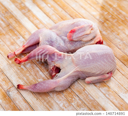 Two uncooked quails on wooden table 140714891