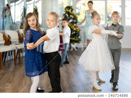 Preteen children in elegant outfits practicing partner dance in Christmas studio Preteen children in elegant outfits practicing partner dance in Christmas studio 140714898