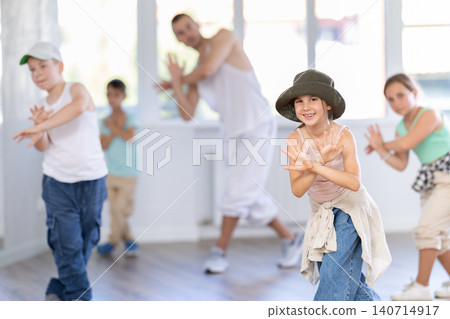 In sports studio, childrens team learns hip-hop dance accompanied by experienced man teacher In sports studio, childrens team learns hip-hop dance accompanied by experienced man teacher 140714917