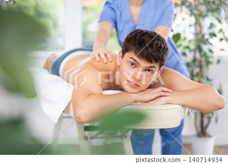 Female massagist doing massage to male client in spa center 140714934