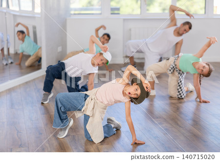 Preteen boys and girls studying movement of contemporary dance in classroom with his friends Preteen boys and girls studying movement of contemporary dance in classroom with his friends 140715020