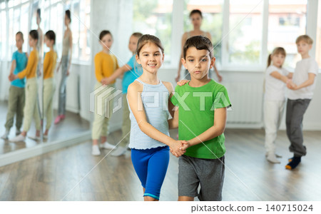 Happy preteen children practicing ballroom dances in pairs in training hall Happy preteen children practicing ballroom dances in pairs in training hall 140715024