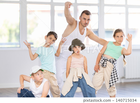 Group portrait of happy preteen hip hop dancers with male choreographer in dance studio 140715034