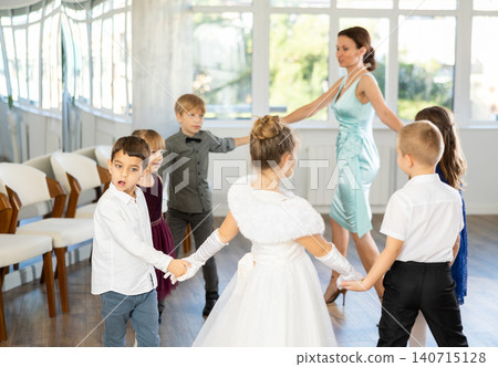 Little children in elegant dresses doing round dance in school hall Little children in elegant dresses doing round dance in school hall 140715128