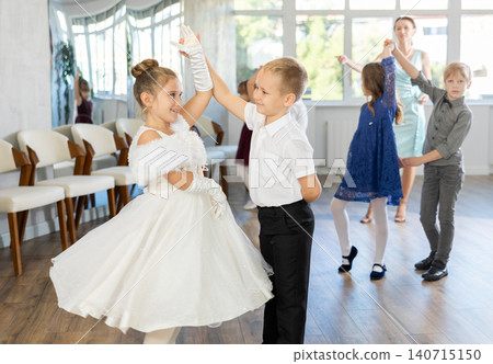 Little children in elegant dresses practicing waltz dance in school hall Little children in elegant dresses practicing waltz dance in school hall 140715150