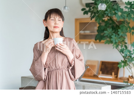中年亞洲婦女在廚房/餐廳喝咖啡/茶 中年亞洲婦女在廚房/餐廳喝咖啡/茶 140715583